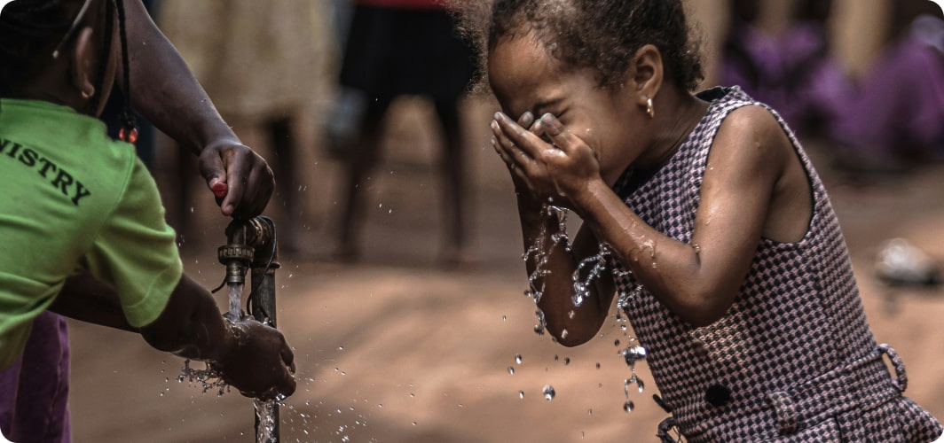 Child washing face while water splashes from a tap