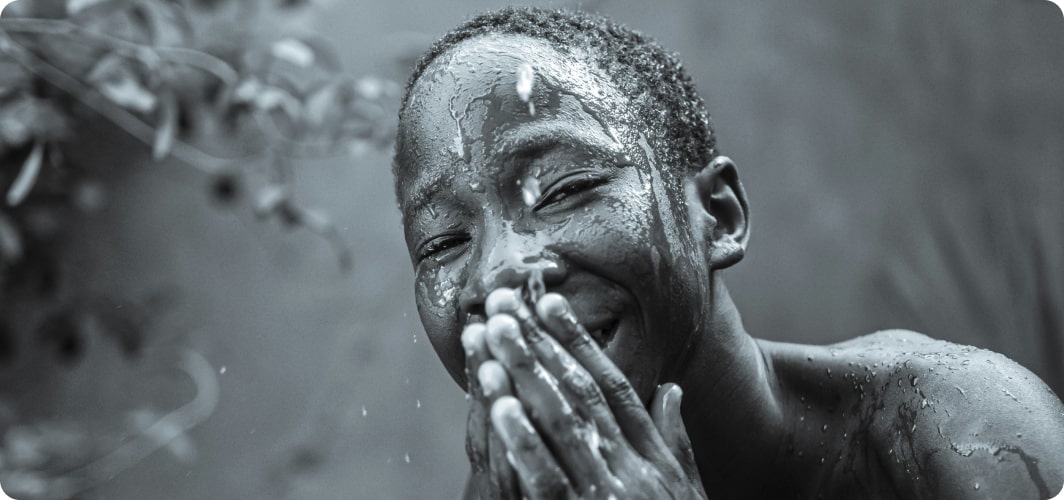 Smiling child washing face with water