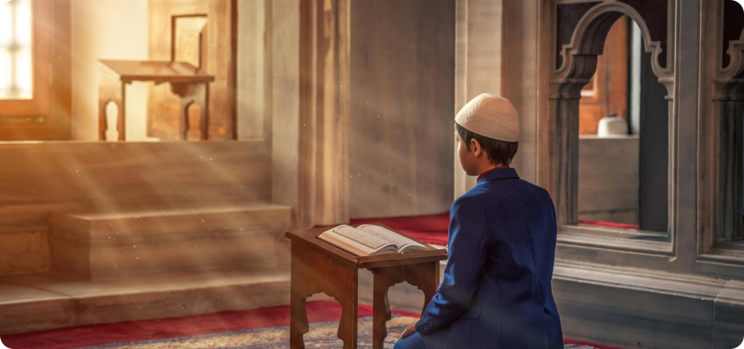 Child praying in a mosque near a Quran stand