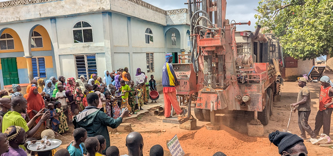 Village with drilling rig and people gathered around